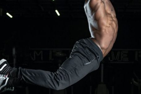 Man Fitness - Man Jumping in Mid Air Holding Blue Ball Above His Head