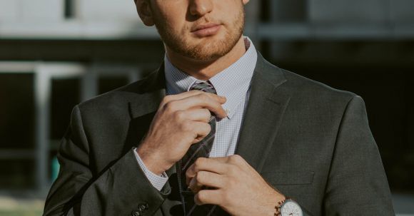 Beard Men - Serious confident male entrepreneur wearing classy suit and wristwatch holding tie while thoughtfully looking away